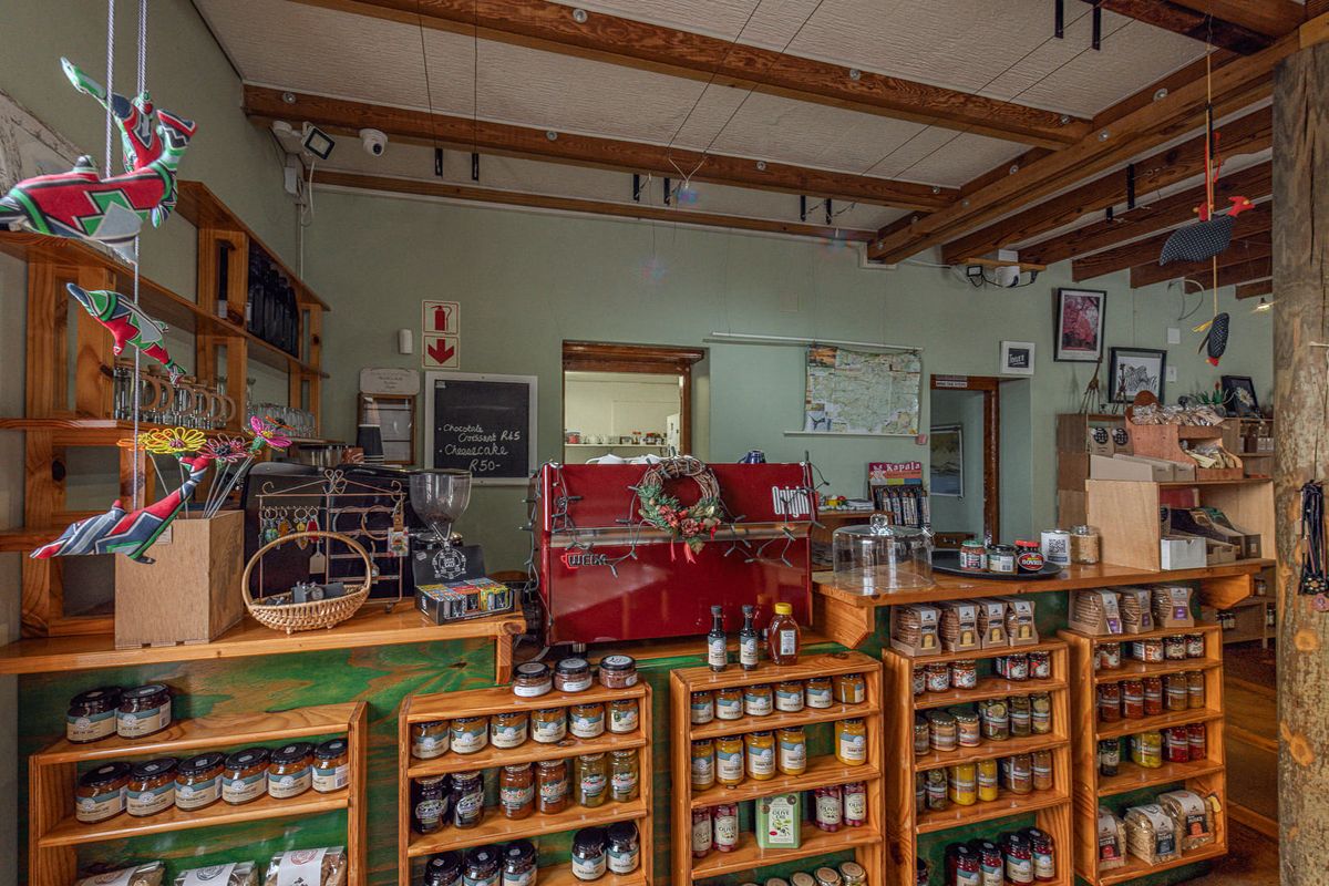 A rustic commercial cafe counter area featuring built-in timber shelving, exposed wooden ceiling beams, and a dedicated coffee preparation station.