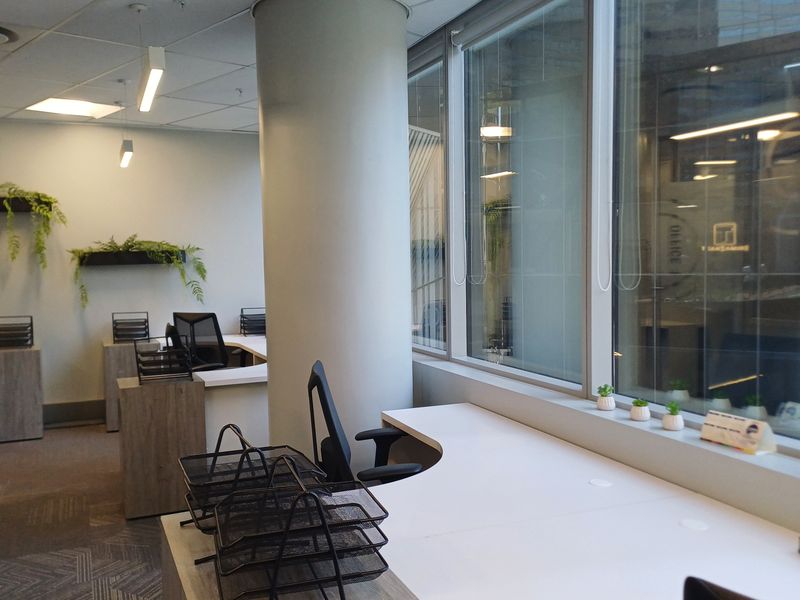 Modern office space featuring built-in desk workstations, large windows providing natural light, and a clean, professional interior finish.