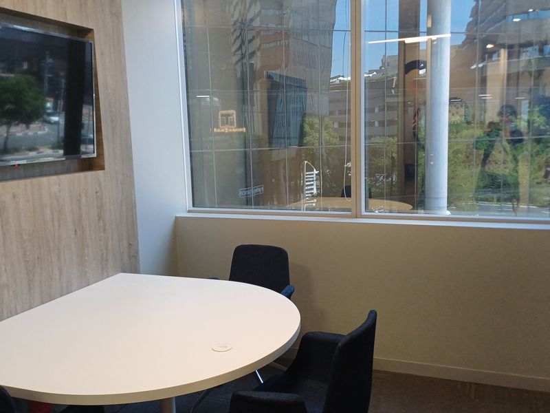 A modern office meeting room featuring a large window with natural light and a dedicated recessed wall area for a display screen.
