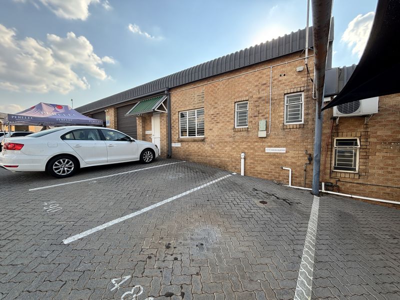 Industrial property exterior featuring a face brick facade, paved parking area, and metal roofing with security window bars.