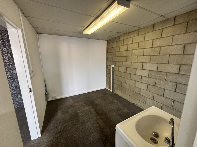 A functional utility space featuring an exposed concrete block wall, drop ceiling, and a built-in utility sink.