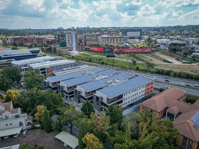 Aerial view of a modern multi-story office complex featuring contemporary architecture, roof-mounted HVAC systems, and surrounding landscaped grounds in a commercial district.