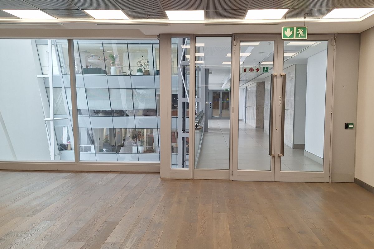 Modern, open-plan office space featuring high-quality timber flooring, recessed LED lighting, and extensive glass partitioning providing natural light and a professional aesthetic.