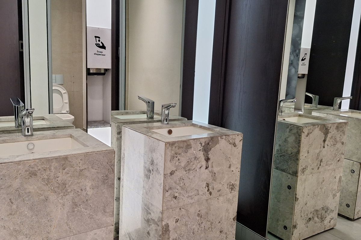 Modern office bathroom featuring high-end marble pedestal sinks, chrome fixtures, and full-height mirrors in a clean, contemporary design.