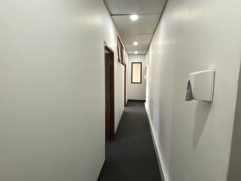 A functional industrial hallway featuring recessed ceiling lighting, carpeted flooring, and wall-mounted utility fixtures.