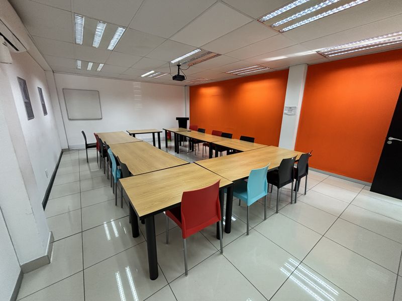 A functional office meeting room featuring tiled flooring, suspended ceiling with recessed lighting, and an integrated air conditioning unit.