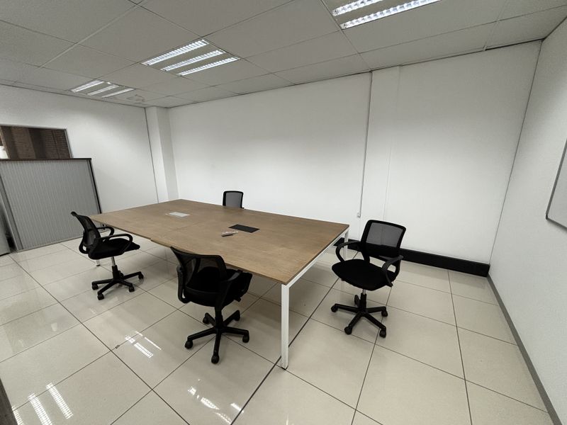 A functional office space featuring tiled flooring, a suspended ceiling with recessed lighting, and clean white walls, suitable for a professional work environment.