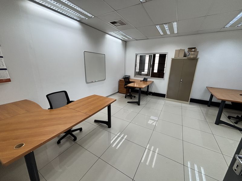 A functional office space featuring ceramic tile flooring, suspended ceilings with recessed lighting, and secure window access.