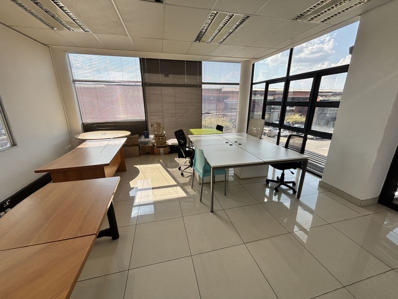 Bright and spacious office area featuring large windows with blinds, suspended ceilings with recessed lighting, and clean tiled flooring.
