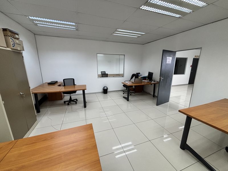 A functional office space featuring ceramic tiled flooring, a suspended ceiling with recessed lighting, and an internal glass partition for visibility.