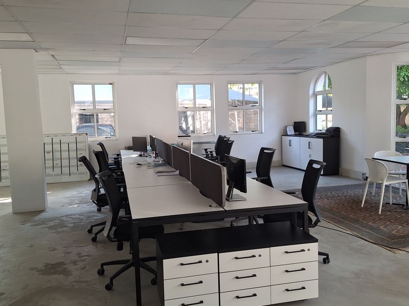 Open-plan office space featuring a suspended ceiling, polished concrete floors, and multiple windows providing natural light.