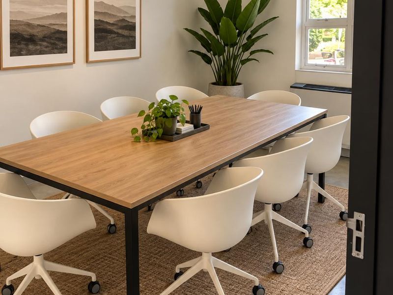 A well-maintained professional office meeting room featuring polished concrete floors, an arched window, and recessed ceiling lighting.