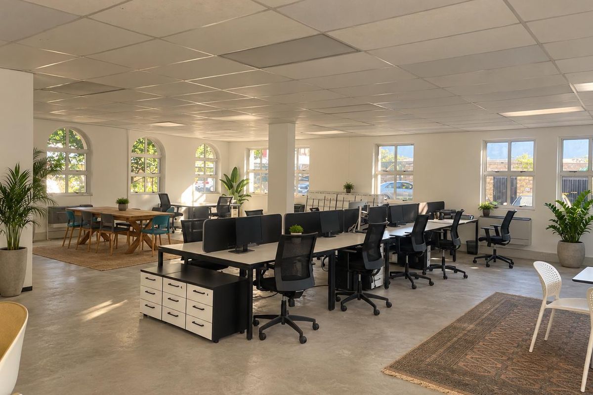 Spacious open-plan office area featuring polished concrete floors, a suspended ceiling, and multiple arched windows providing ample natural light.