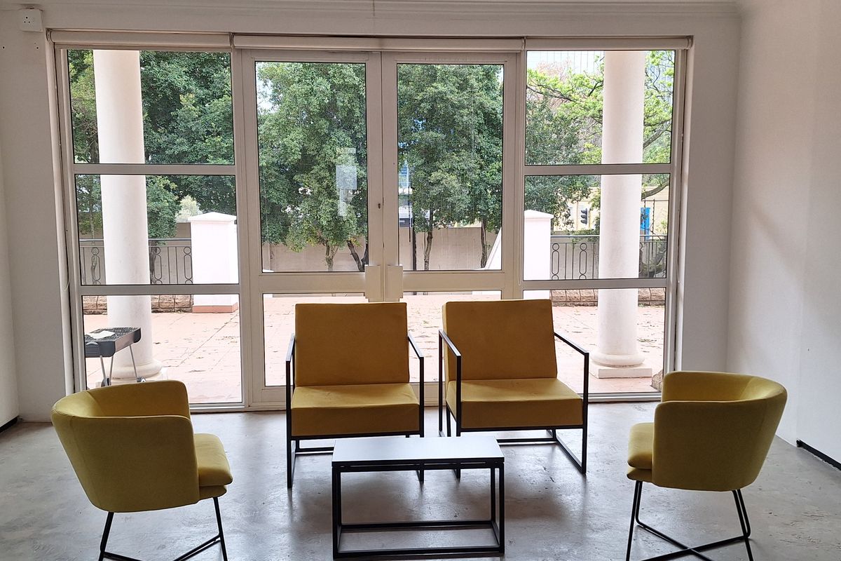 A bright office space featuring polished concrete floors, recessed lighting, and large glass doors opening onto an outdoor patio area.