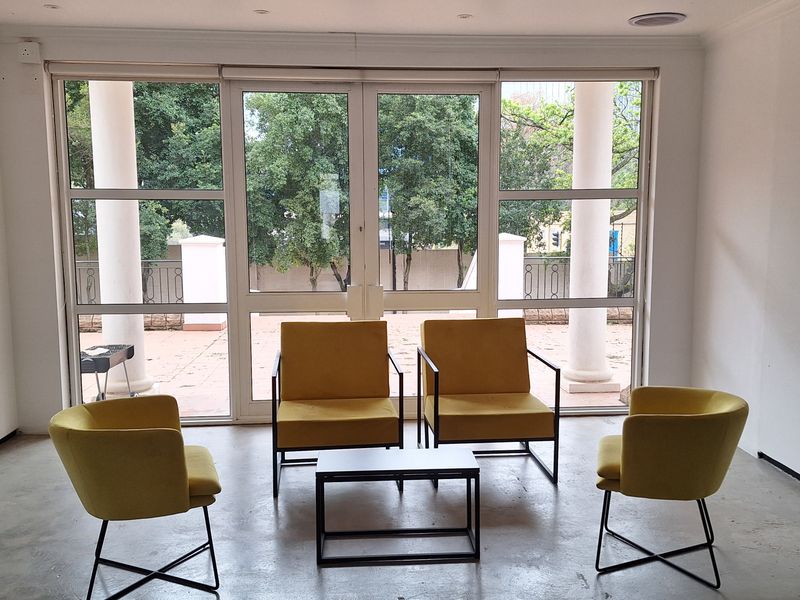A bright office space featuring polished concrete floors, recessed lighting, and large glass doors opening onto an outdoor patio area.