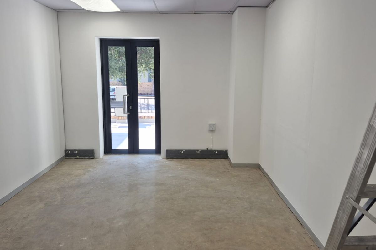 A vacant office space featuring a drop ceiling, recessed lighting, and a double glass door leading to the exterior.