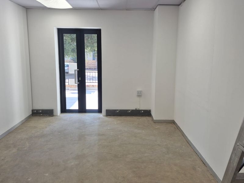 A vacant office space featuring a drop ceiling, recessed lighting, and a double glass door leading to the exterior.