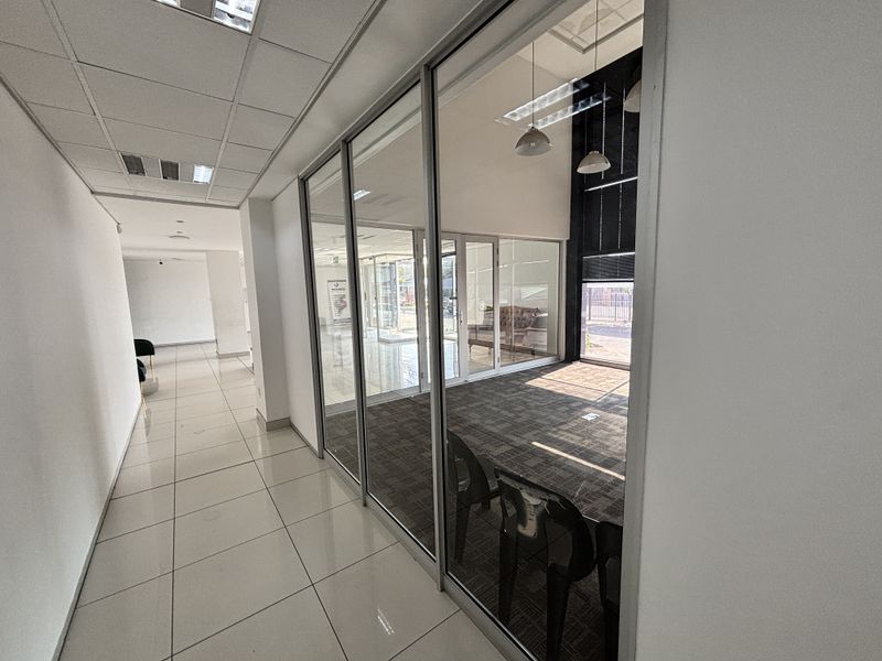 Modern office space featuring glass partitions, suspended ceilings, and a combination of tiled and carpeted flooring, offering a clean and professional industrial workspace.