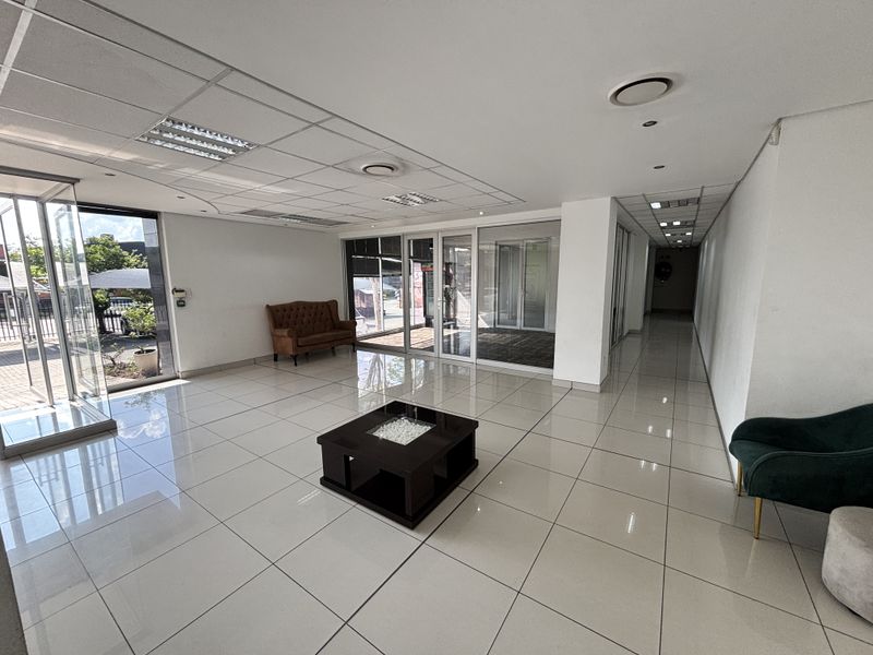 Spacious industrial entrance lobby featuring polished tiled flooring, suspended ceilings with recessed lighting, and large glass doors providing ample natural light.