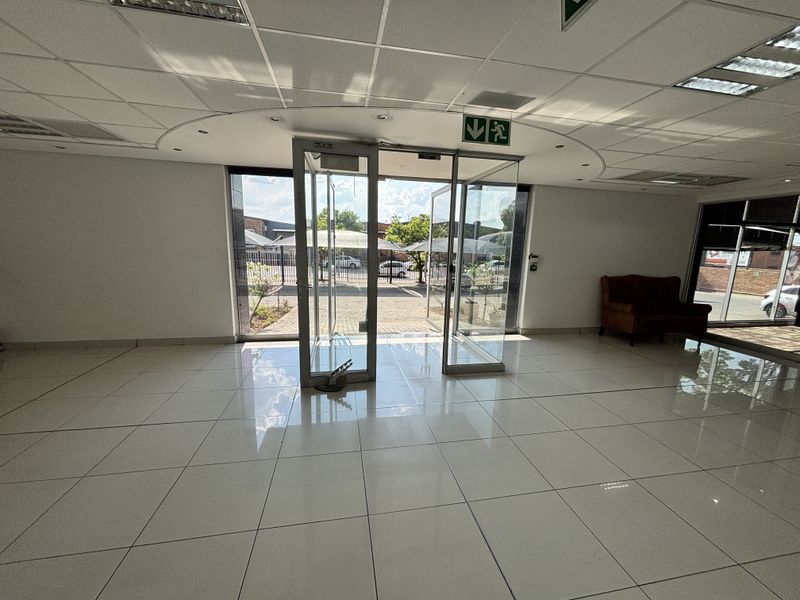 Spacious and bright industrial entrance lobby featuring polished tiled flooring, a modern suspended ceiling, and large glass doors leading to the exterior parking area.