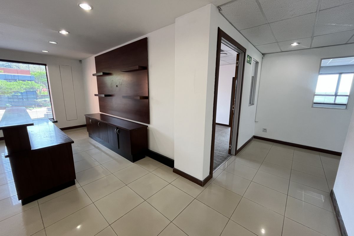 A bright, open-plan office space featuring tiled flooring, recessed lighting, and built-in cabinetry, offering a clean and professional environment.