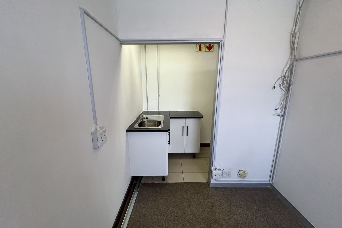 A compact office kitchenette featuring built-in cabinetry, a stainless steel sink, and laminate countertops, providing essential utility space within the office environment.