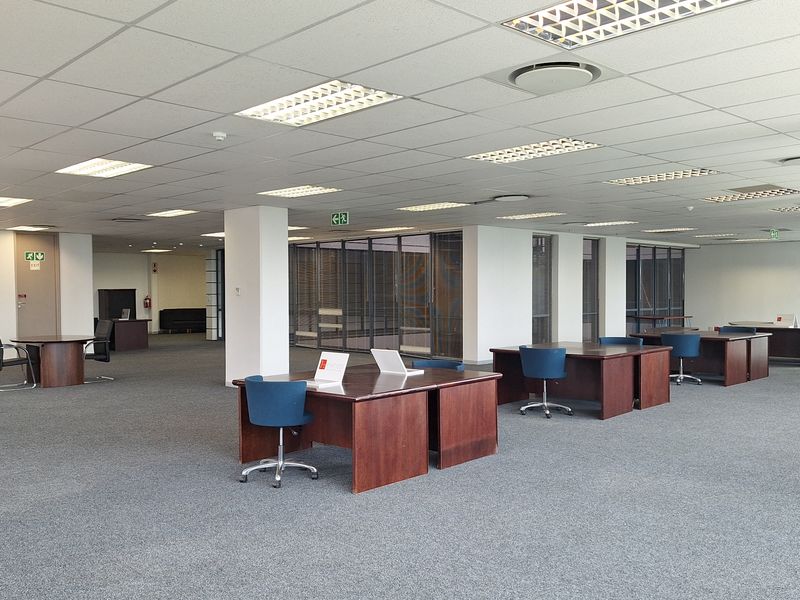 Spacious open-plan office area featuring a suspended ceiling, recessed lighting, integrated air conditioning, and carpeted flooring with glass partition walls.