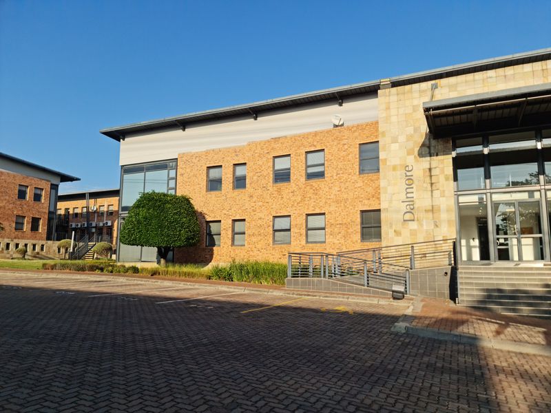 Front exterior view of the Dalmore office building featuring a brick and stone facade, paved parking area, and an accessible entrance ramp.