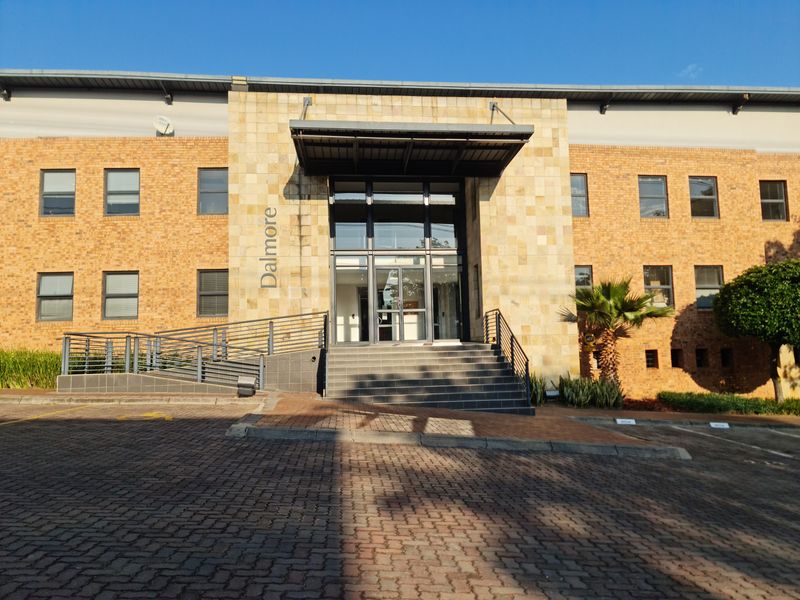 Front elevation of the Dalmore office building featuring a brick and stone facade, glass entrance, and accessible ramp.