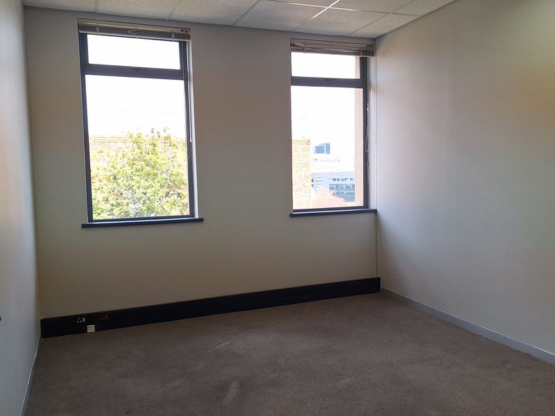 A vacant office space featuring a suspended ceiling with recessed lighting, carpeted flooring, and integrated electrical skirting trunking.