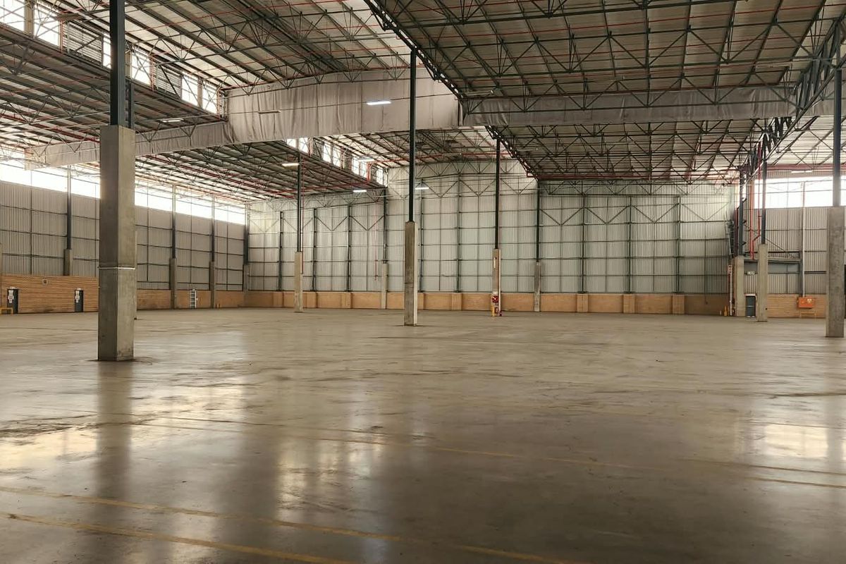 A spacious, open-plan industrial warehouse featuring high ceilings, concrete flooring, and robust steel structural supports, suitable for logistics or manufacturing operations.