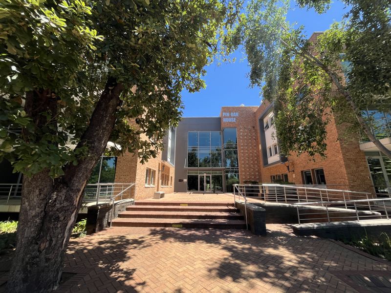 Front entrance of Pin Oak House featuring a modern brick and glass facade with paved access steps and metal handrails.
