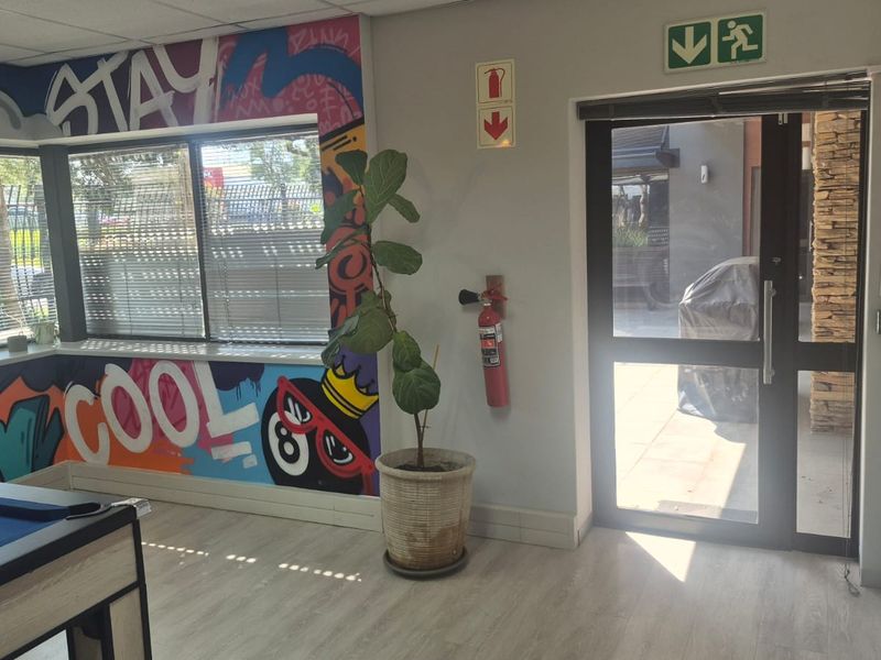 Office space featuring laminate flooring, a drop ceiling, and an aluminium-framed glass door leading to an outdoor area.