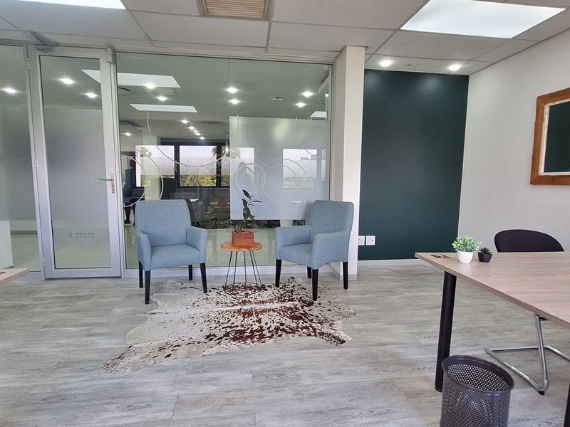 Modern office space featuring a glass partition wall, suspended ceiling with recessed lighting, and durable laminate flooring, creating a professional and bright work environment.