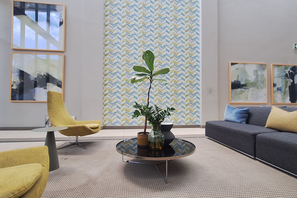 A modern, well-lit office lounge area featuring a decorative patterned feature wall and neutral tiled flooring.