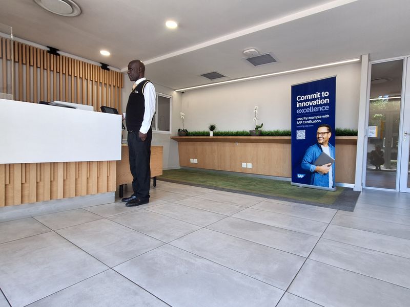 Modern office reception area featuring a custom timber-paneled desk, neutral tiled flooring, and bright recessed lighting, creating a professional and welcoming entrance space.