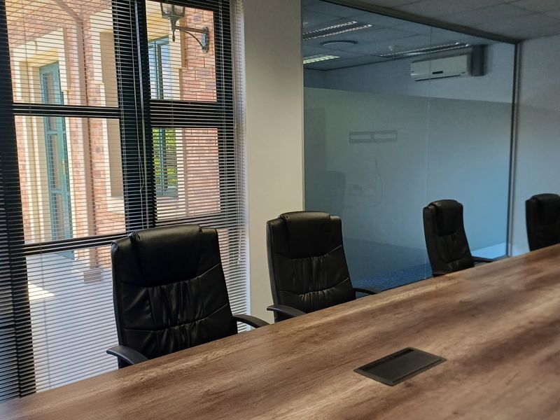 A professional office meeting room featuring a glass partition wall, modern carpet flooring, and integrated air conditioning for a comfortable workspace environment.
