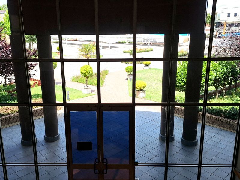 Entrance area featuring a large glass curtain wall providing views of the landscaped courtyard and paved patio.