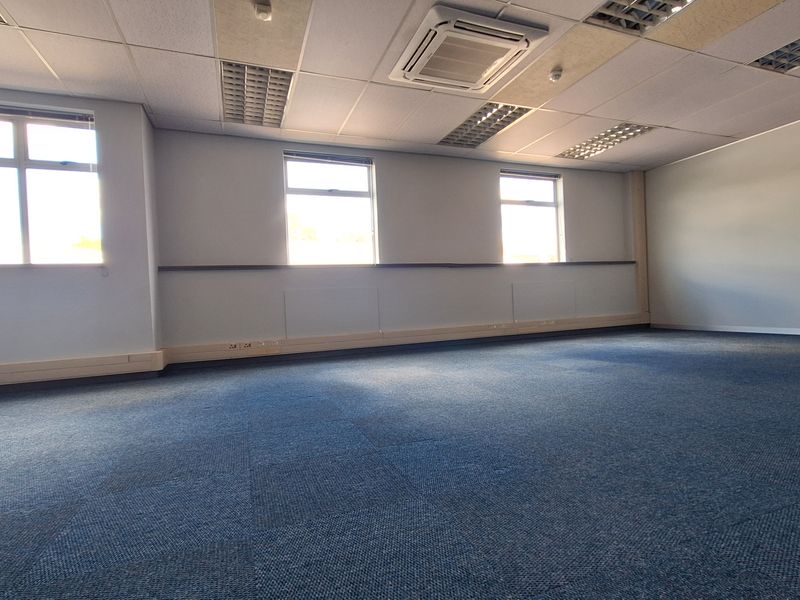 Spacious open-plan office area featuring suspended ceilings, recessed lighting, integrated air conditioning, and perimeter trunking for flexible workstation connectivity.
