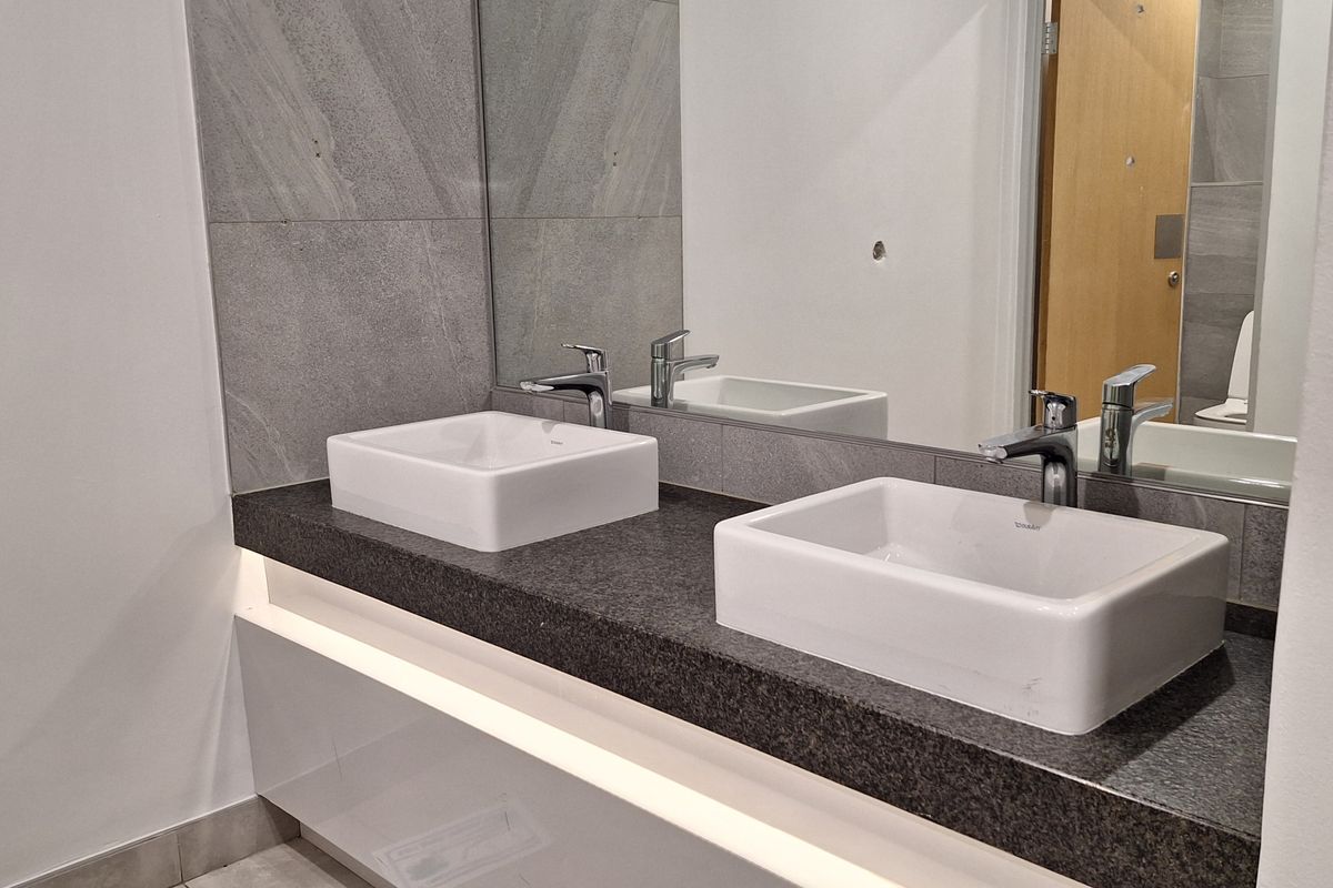 Modern bathroom featuring a double vanity with vessel sinks, stone countertop, and integrated under-cabinet lighting.