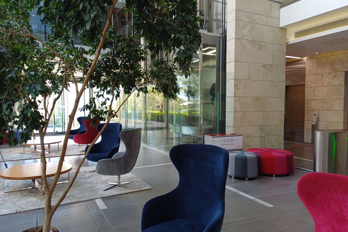 A modern office building lobby featuring high-end stone wall finishes, expansive glass facades, and polished tile flooring in a professional, well-maintained environment.
