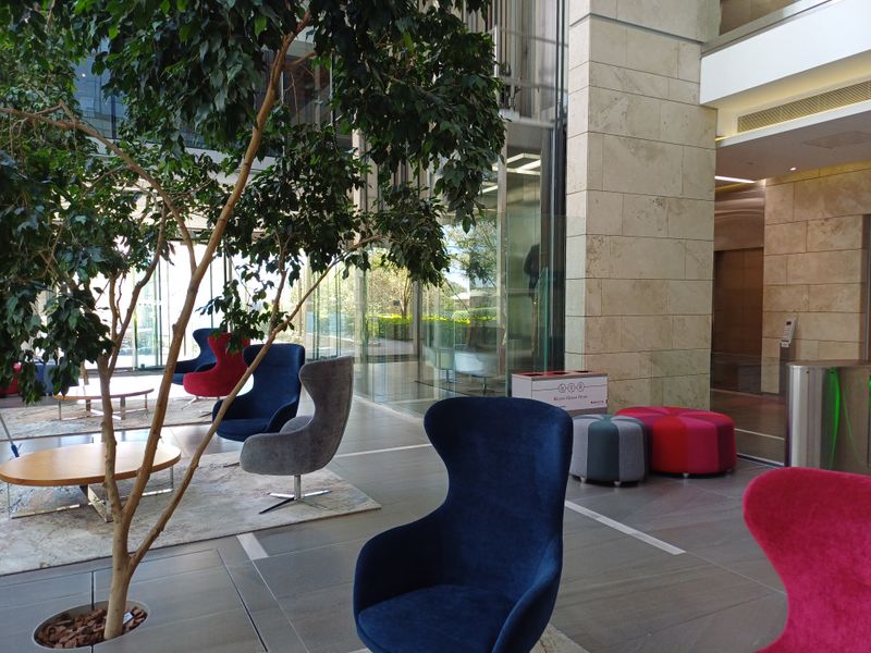 A modern office building lobby featuring high-end stone wall finishes, expansive glass facades, and polished tile flooring in a professional, well-maintained environment.