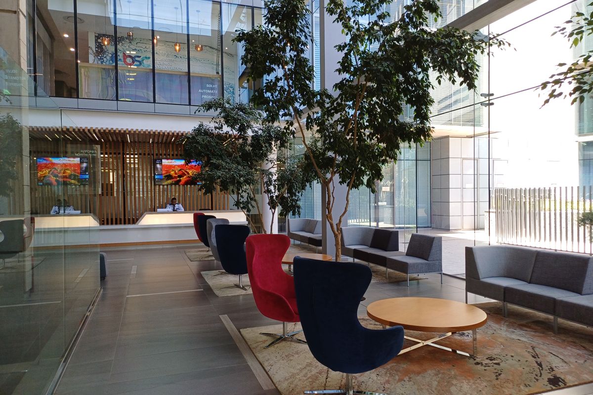 Modern office building lobby featuring a reception desk, floor-to-ceiling glass walls, and contemporary architectural finishes in a bright, open-plan layout.