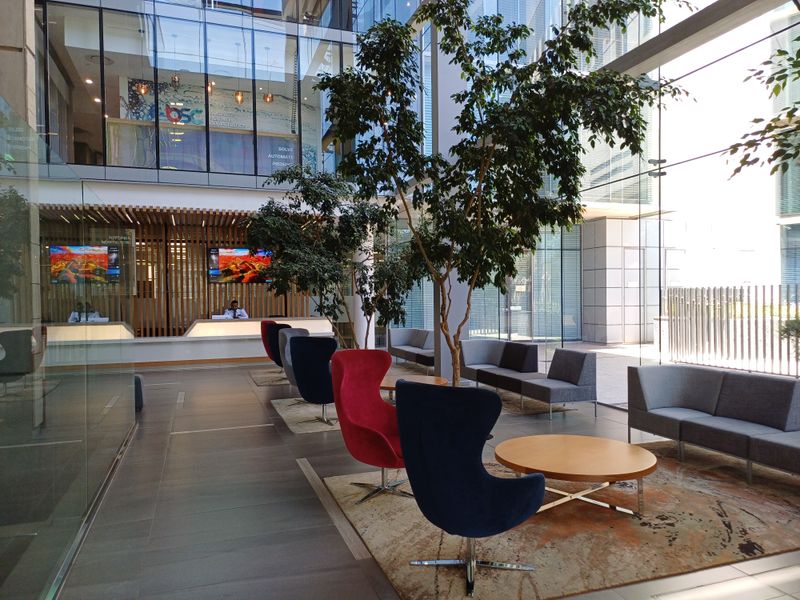 Modern office building lobby featuring a reception desk, floor-to-ceiling glass walls, and contemporary architectural finishes in a bright, open-plan layout.