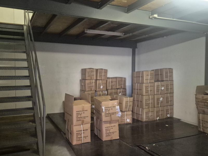 Industrial utility space featuring a steel mezzanine level with integrated staircase and overhead fluorescent lighting, suitable for storage or operational use.