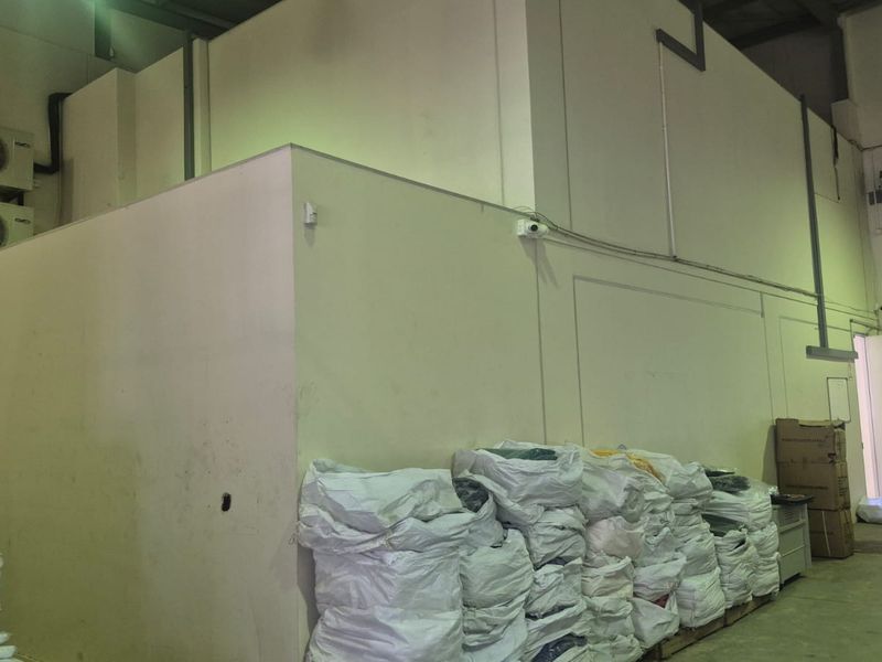 Industrial utility space featuring high ceilings, roller shutter door access, and wall-mounted air conditioning units, suitable for storage or operational use.