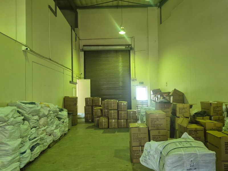 Industrial warehouse space featuring high ceilings, concrete flooring, and a large roller shutter door for efficient loading and access.