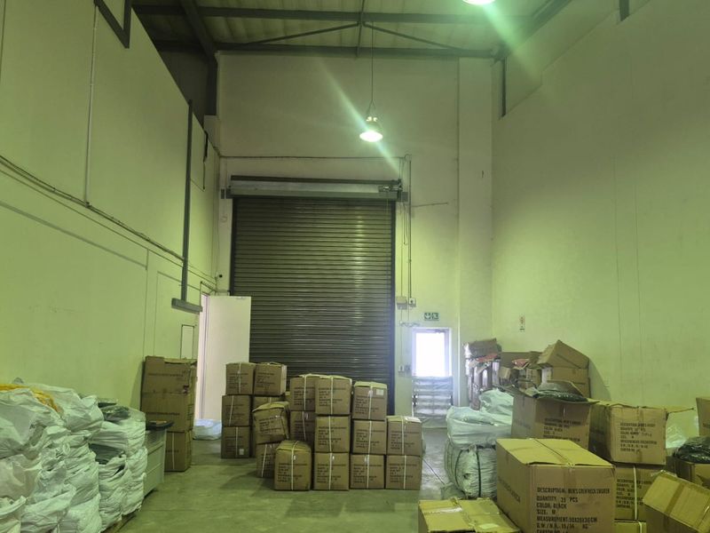 Industrial warehouse unit featuring high ceilings, concrete flooring, and a large roller shutter door for efficient loading and access.