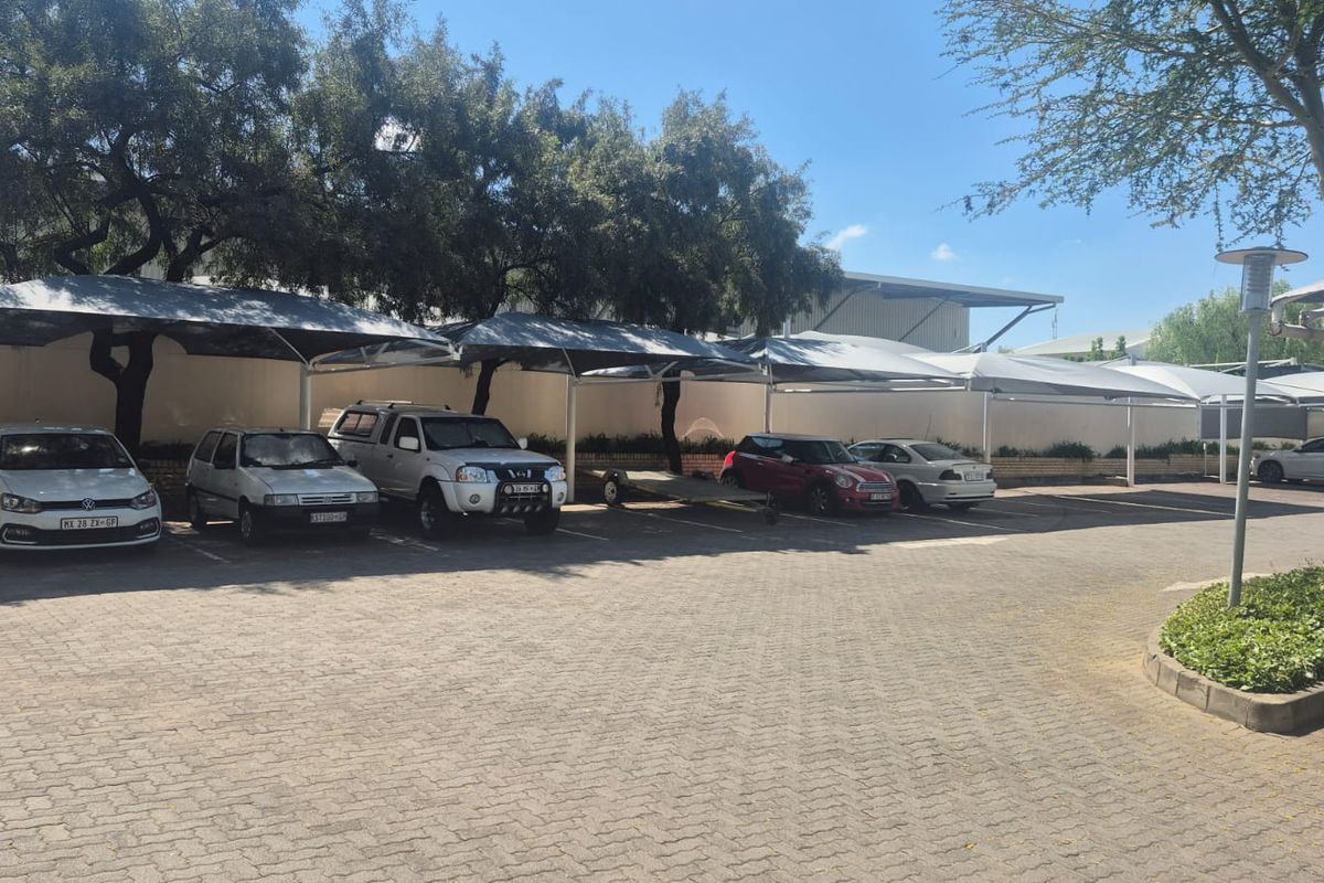 Industrial property exterior featuring a paved parking area with multiple shade cloth carports and established perimeter landscaping.