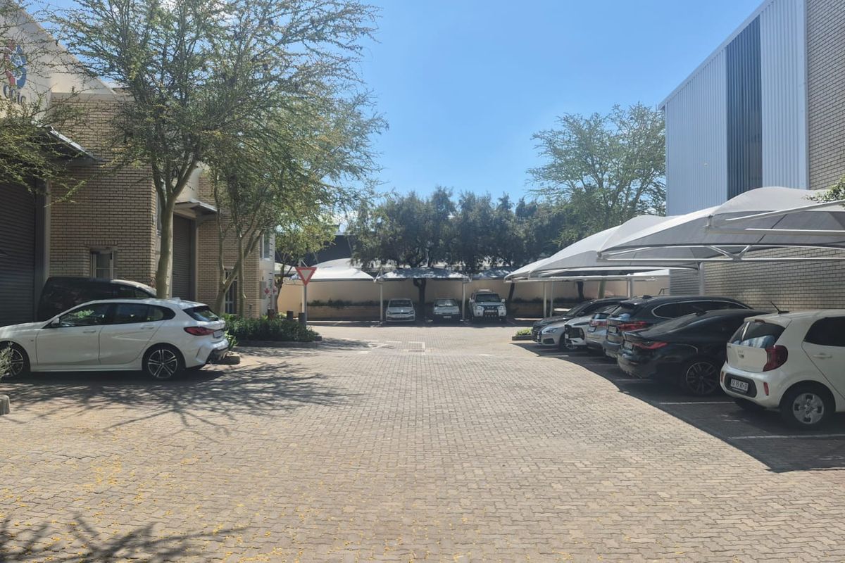 Industrial property exterior featuring a paved parking area with multiple shade cloth carports and brick warehouse structures.